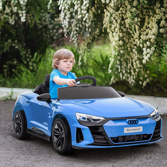 A young boy driving the blue kids electric car outdoors on a paved path with trees behind him