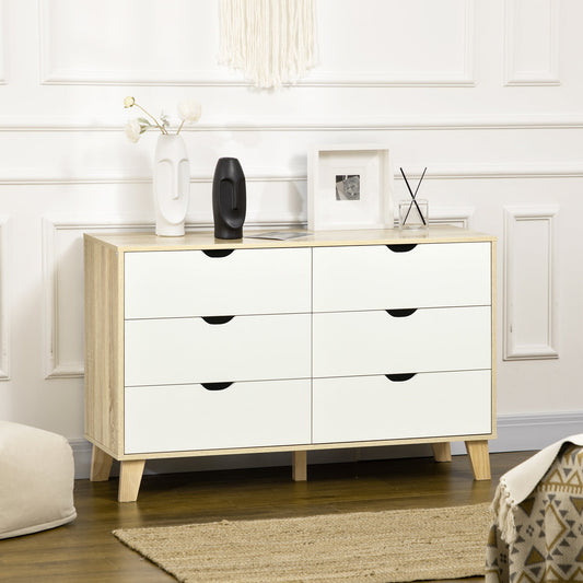 A white six-drawer dresser with light brown wood effect frame and legs, shown in a stylish living room setting