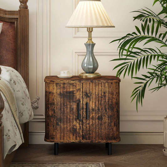Rustic brown bedside cabinet with a lamp and plant on top, placed next to a bed