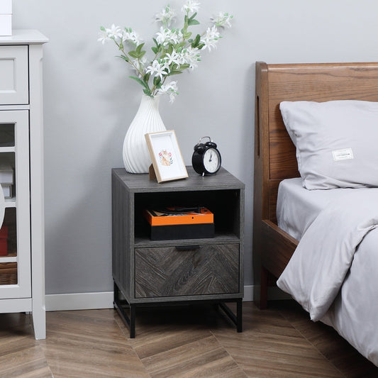The dark grey bedside table with drawer and shelf next to a bed, with a vase and clock on top