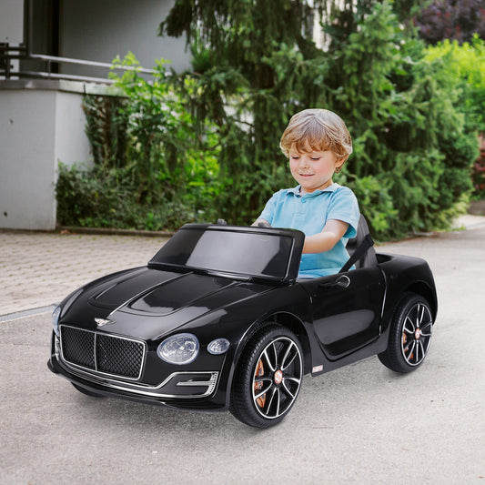 A young boy happily driving the black kids electric car on a paved path outdoors