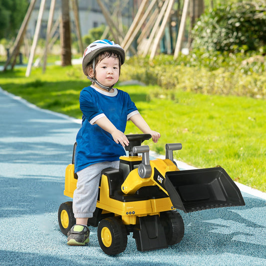 A young child wearing a helmet sitting on the yellow construction ride-on toy outdoors