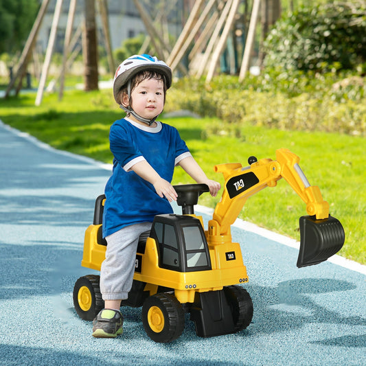 A young child wearing a helmet rides the yellow CAT digger toy on a paved path outdoors