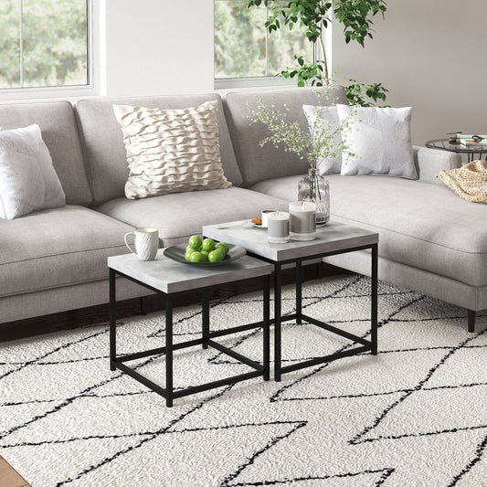The grey nesting coffee tables are arranged in a living room setting on a rug