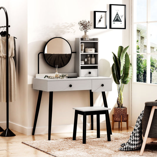 The grey dressing table set with mirror and stool is shown in a bedroom setting with a chair and plant
