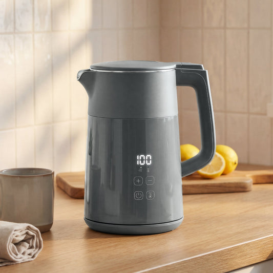 The water kettle sitting on a wooden kitchen counter next to a mug and fresh lemons