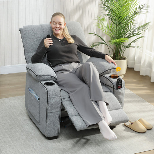 A woman relaxing in the grey electric massage recliner armchair with vibration, holding a remote control