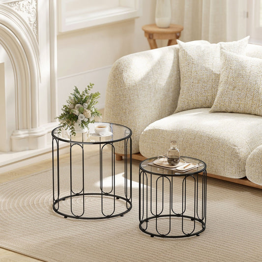 Two round glass top tables with black metal frames in a living room setting