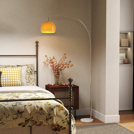 Orange floor lamp in a bedroom next to a bed and bedside table