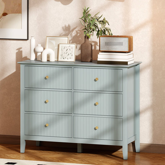 The light green six-drawer chest of drawers in a stylish room with decorative items on top