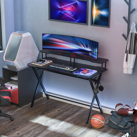 The office desk set up in a modern bedroom with a computer and gaming gear
