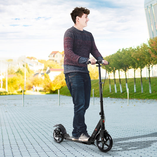 A young man riding the black two-wheel scooter on a paved path outdoors