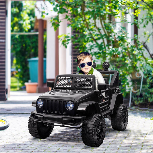 A young boy wearing sunglasses drives the black electric ride-on car on a paved path outdoors