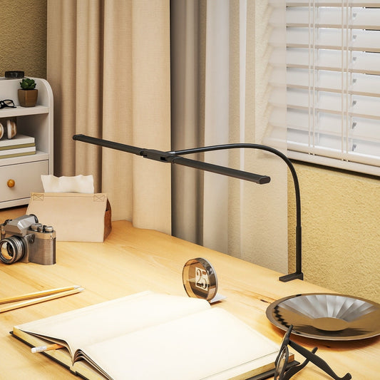 The desk lamp is on a wooden desk next to an open book and a camera