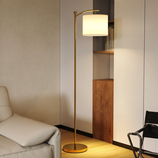 The gold tone floor lamp standing next to a sofa and a chair in a living room