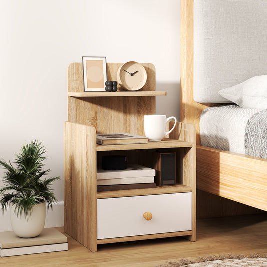 The storage cabinet placed next to a bed with a plant and a mug on top