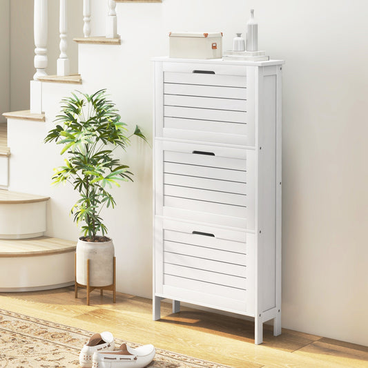 The narrow shoe cabinet with three flip drawers placed in a hallway next to stairs with a plant and shoes