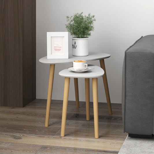 The side tables placed in a living room next to a grey sofa with a plant and a coffee cup