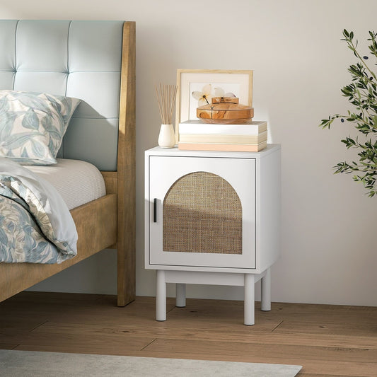 White rattan bedside table next to a bed in a bedroom setting