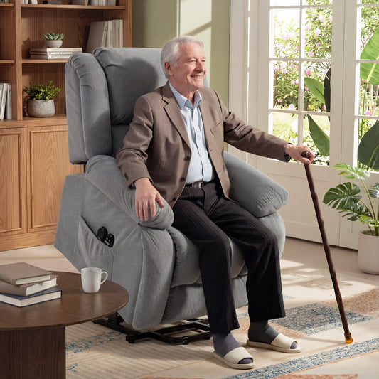 An elderly man sitting in the light grey massage chair in a bright living room