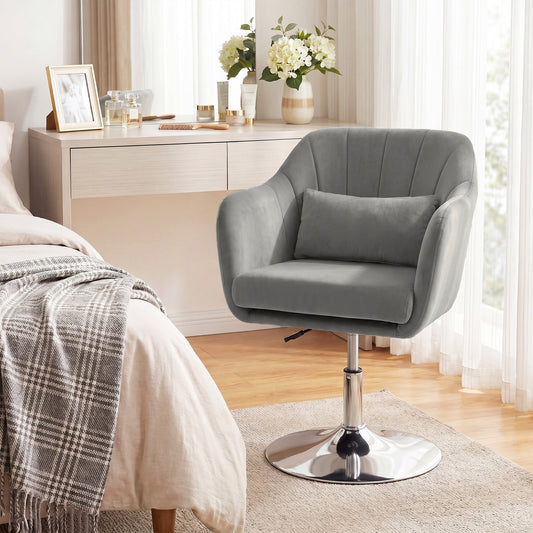 The grey velvet armchair in a bedroom setting next to a dressing table and bed