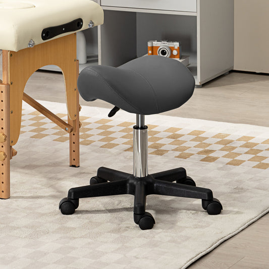 The grey PU leather saddle stool is shown next to a massage table in a room setting