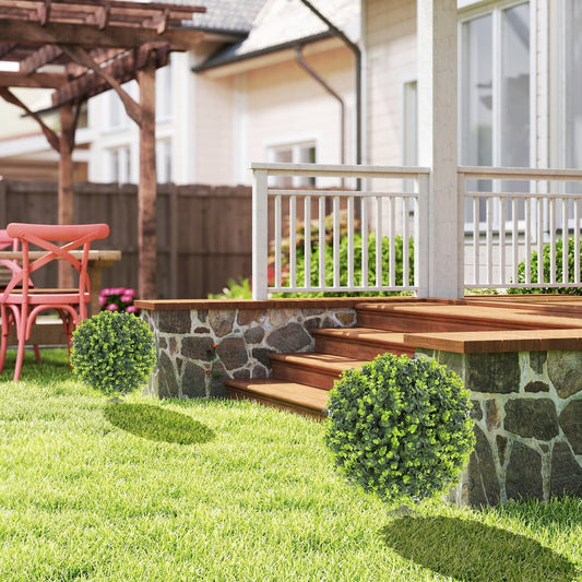 Two artificial boxwood topiary balls placed on a lawn next to a patio