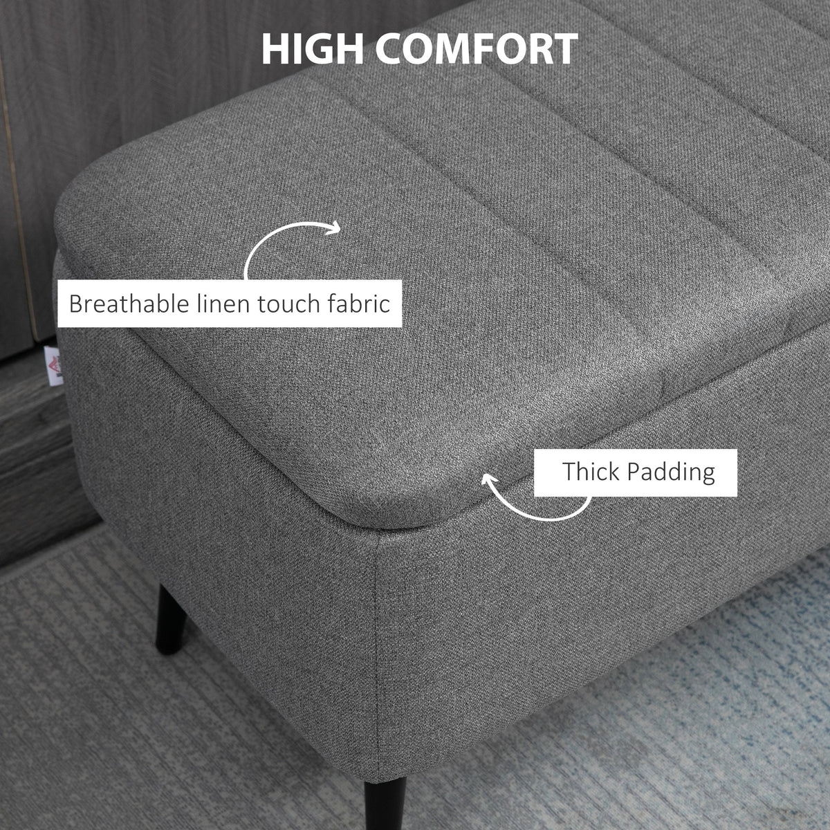 Close-up of the grey upholstered bench showing its linen look fabric and thick padding