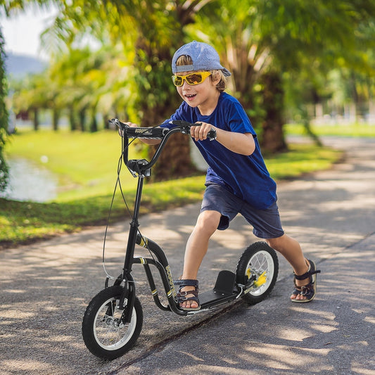 A young boy riding the black stunt scooter outdoors on a paved path