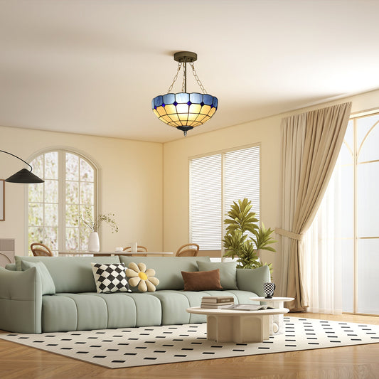 The Tiffany style ceiling light is lit in a modern living room with a large sofa and coffee table