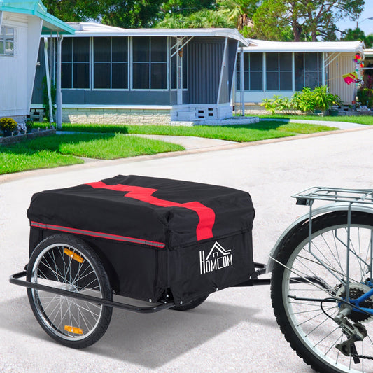 The cargo trailer attached to a bicycle on a paved driveway in front of a house