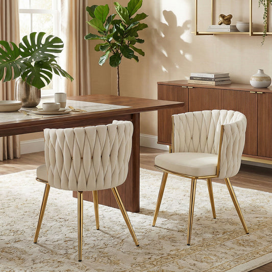 Two cream velvet-feel dining chairs with gold legs placed either side of a wooden dining table