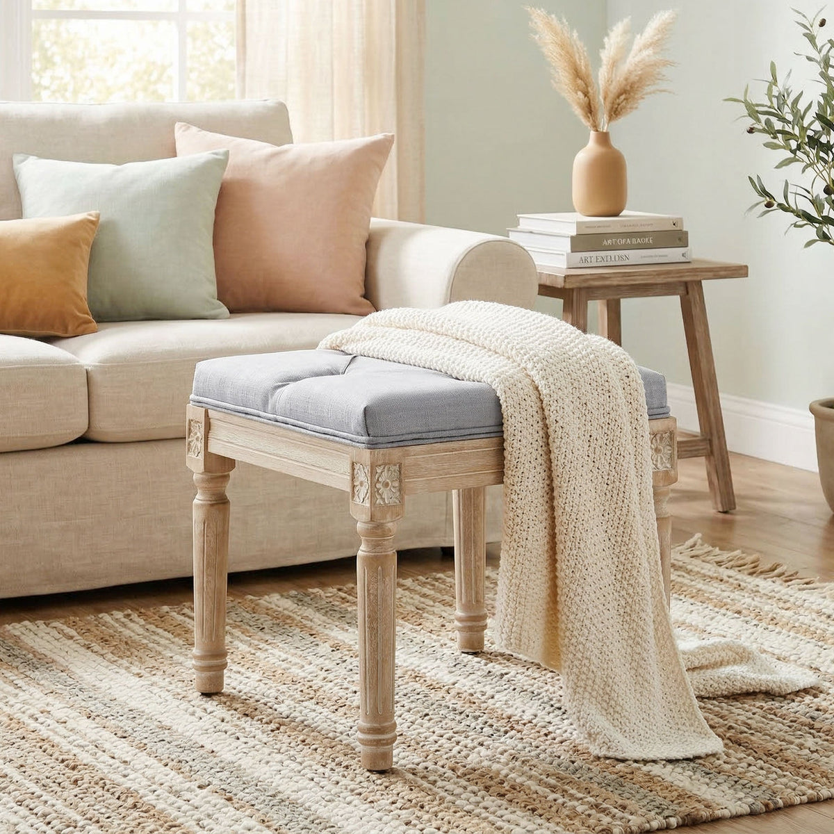 The tufted footrest is placed in a lounge area next to a sofa with a throw blanket draped over it