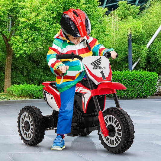 A child wearing a helmet and colourful jacket rides the red electric toy motorbike outdoors on a paved area