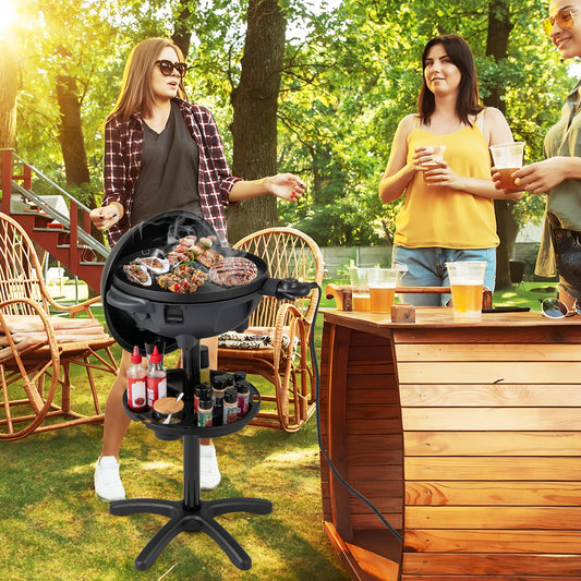 The outdoor grill in use at a garden party with friends standing around in the sunshine