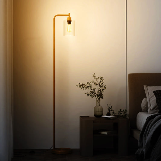 The golden floor lamp stands next to a bedside table in a dimly lit bedroom setting