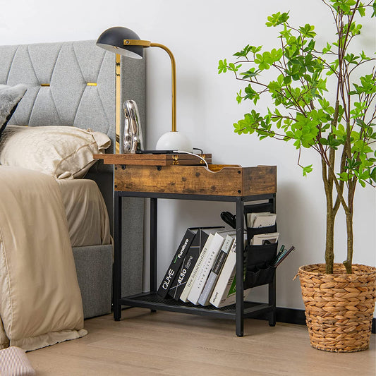 The end table placed beside a bed with a lamp and books on the shelf and in the side pocket