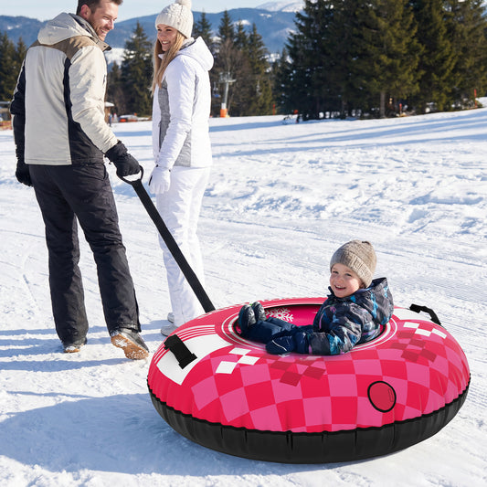 A man pulls a child sitting in the pink inflatable snow tube up a snowy slope