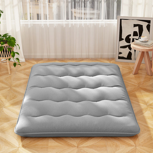 The grey double size floor mattress is laid out flat on a wooden floor near a window