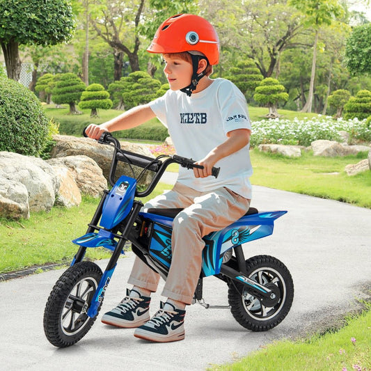 A young boy wearing a helmet riding the electric motorbike on a paved path in a park
