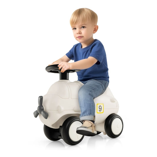 A young boy sitting on the push and pedal ride on toy in a bright indoor setting