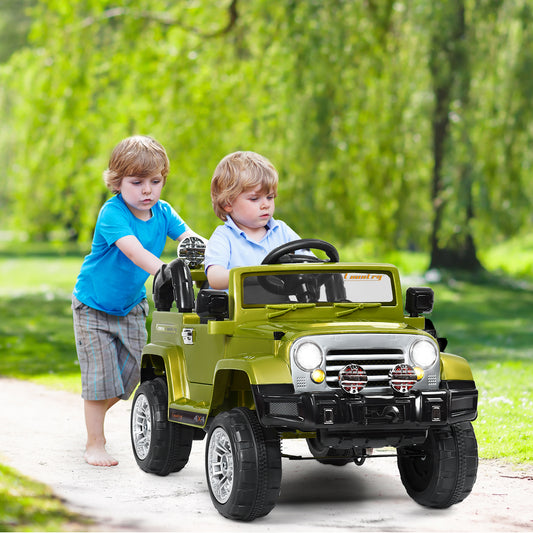 A green kids ride on jeep car with two boys, one pushing and one sitting in the driver's seat