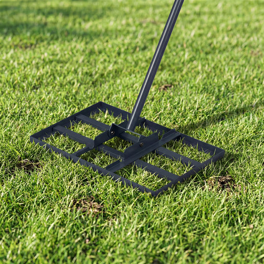 Close-up of the metal plate of the lawn leveling rake resting on green grass