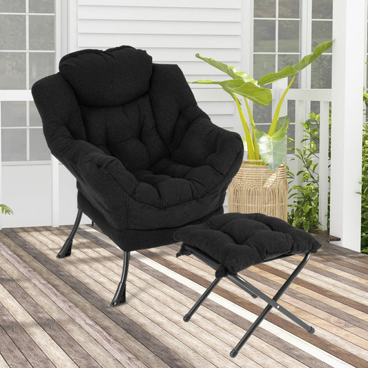 The black accent chair and footrest sit on a wooden deck outside a house