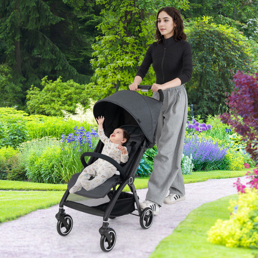 A woman pushes a baby in the grey stroller down a garden path