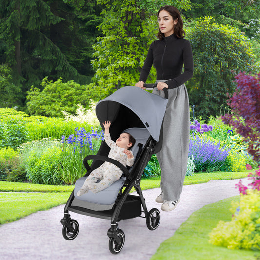 A woman pushes a baby in the light grey stroller along a garden path