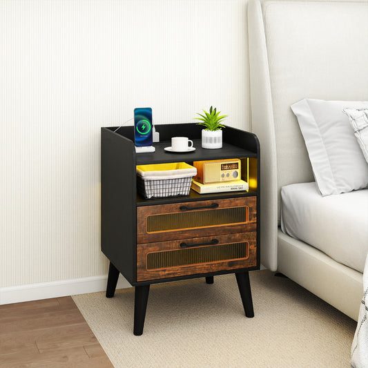 The bedside table placed next to a bed with a phone charging on the top surface