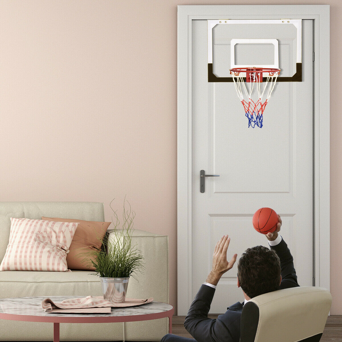 A man playing with the mini basketball hoop with shatterproof backboard in a living room