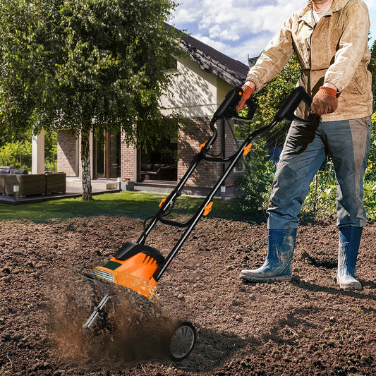 A person using the orange and black electric tiller to cultivate soil in a garden