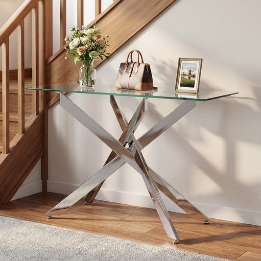 Console table with a glass top and silver criss-cross legs placed in a hallway